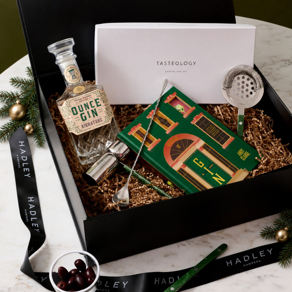 The Christmas Gin Stylist hamper with Ounce Signature Gin, House of Gin book and Tasteology cocktail tools in a black gift box