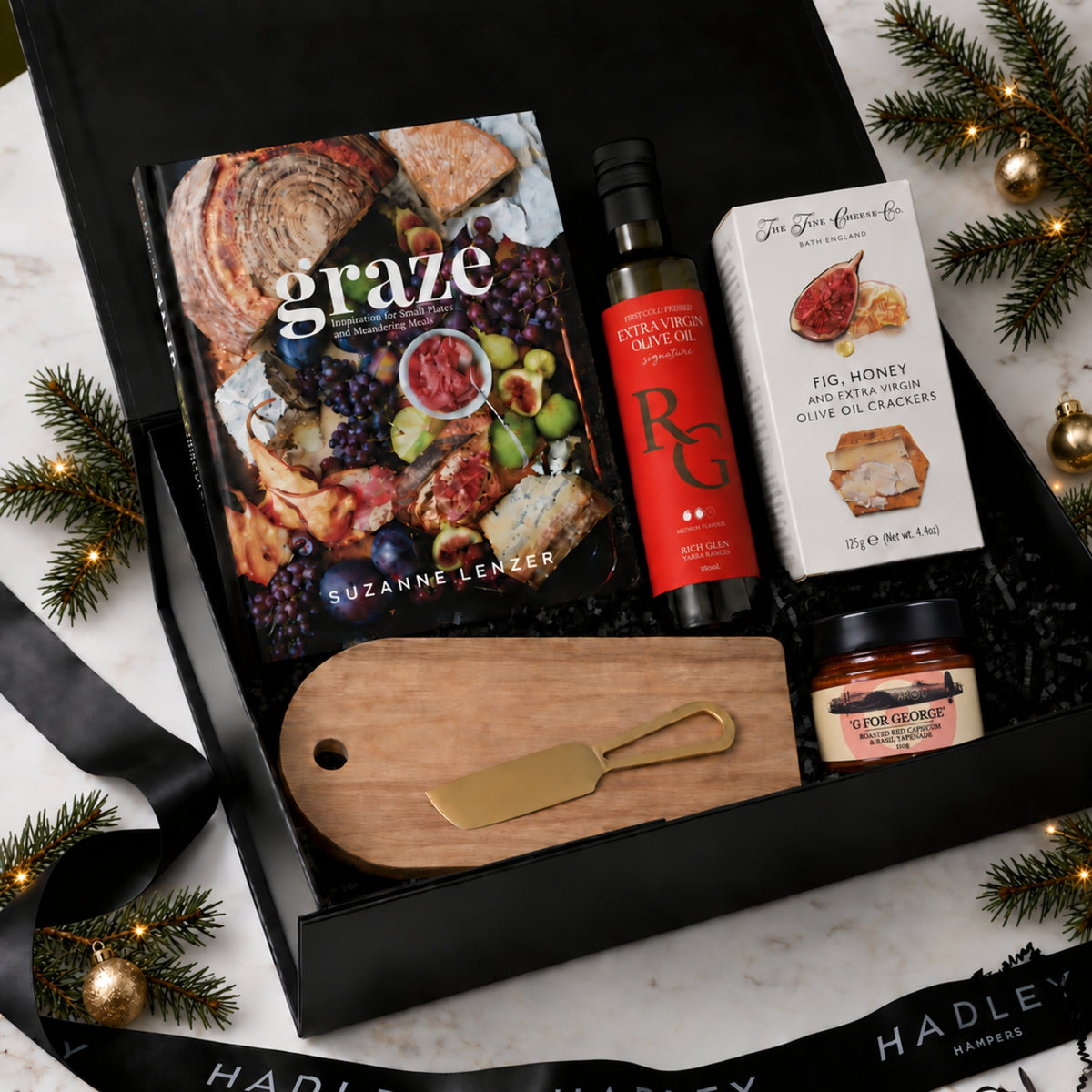Christmas grazing hamper with Graze cookbook, olive oil, fig and honey crackers, roasted capsicum tapenade, cheeseboard and gold cheese knife.