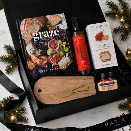 Christmas grazing hamper with Graze cookbook, olive oil, fig and honey crackers, roasted capsicum tapenade, cheeseboard and gold cheese knife.
