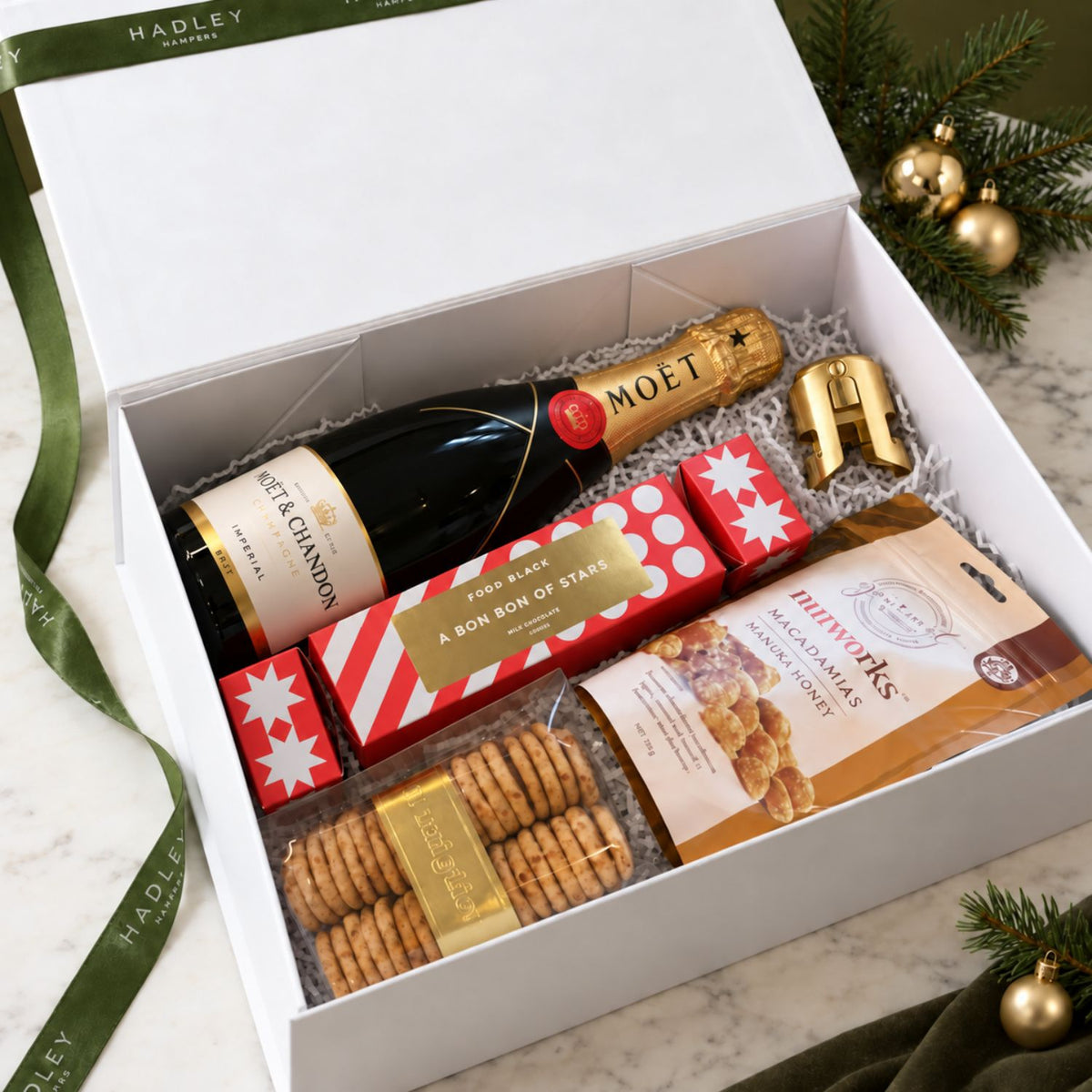 Christmas champagne hamper with Moët, Koko Black chocolate bon bon, honey macadamias, crackers and a gold champagne stopper.