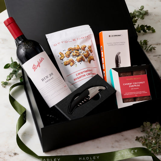 Shiraz Sophisticate hamper with Penfolds Bin 28 Shiraz, Ottolenghi cashews, Koko Black Cherry Coconut Surprise chocolate and Le Creuset corkscrew in a black gift box.